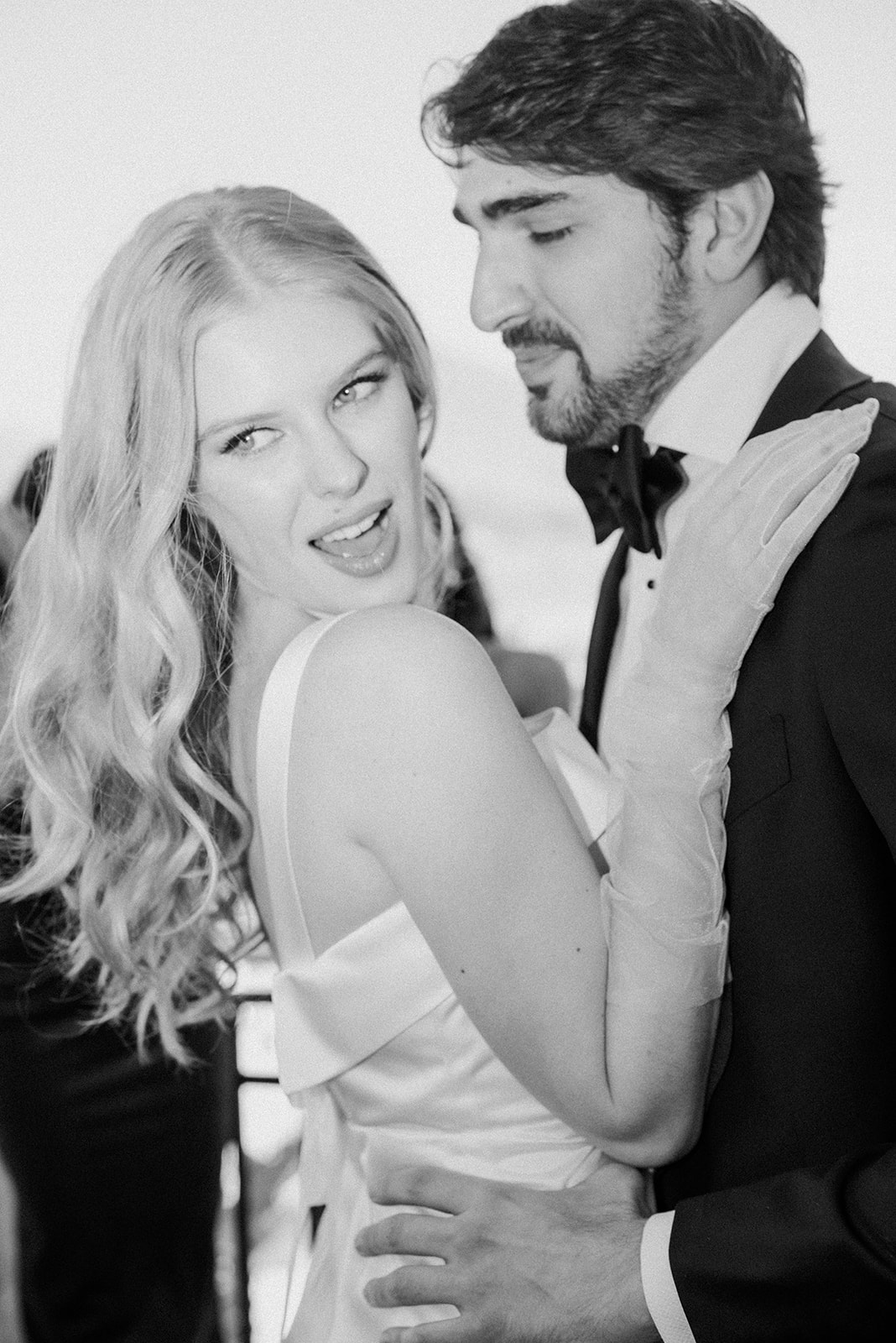 Eine Frau in einem weissen Kleid posiert spielerisch mit einem lächelnden Mann im Anzug bei einer formellen Veranstaltung und fängt die Freude an der Hochzeitsplanung in der Schweiz ein.