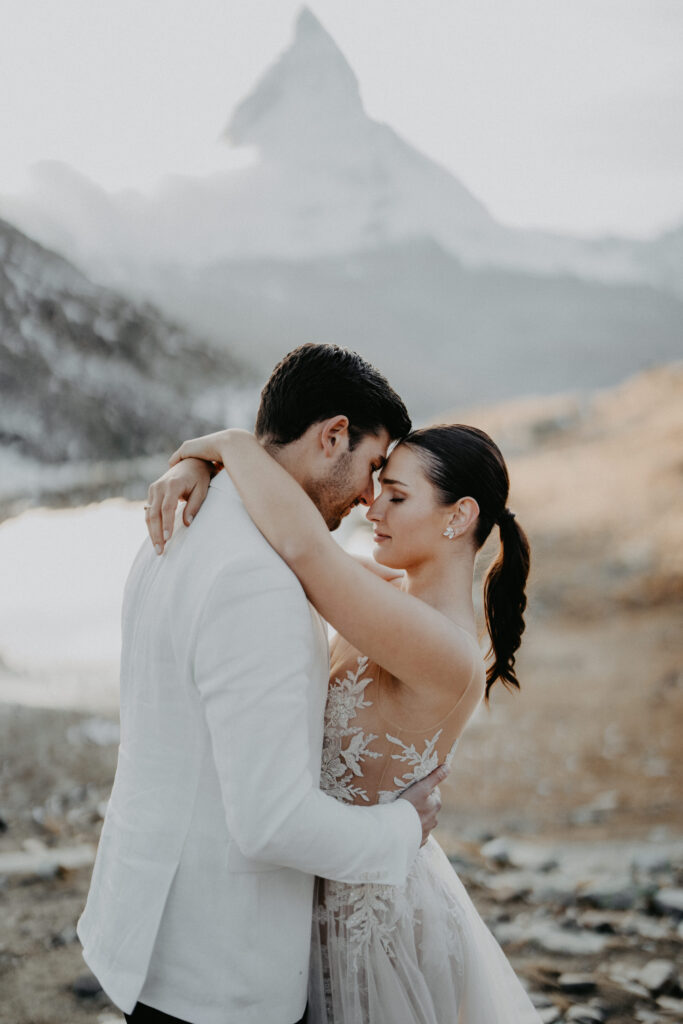 Braut und Bräutigam umarmen sich im Freien mit Matterhorn in Zermatt im Hintergrund und schaffen einen magischen Moment, der perfekt für jede Hochzeitsplanung in der Schweiz ist. Heiraten in der Schweiz!