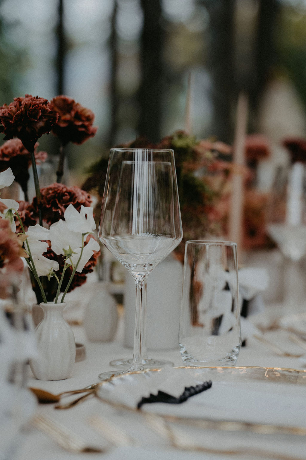 Home 42 Elegant gedeckter Tisch mit Wein- und Wassergläsern, weißen Tellern und rot-weißen Blumenarrangements - die perfekte Inspiration für die Hochzeitsplanung in der Schweiz.