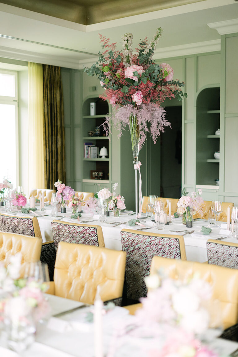 Ein eleganter Esstisch mit gelben Stühlen, rosafarbenen Blumen und sanftem natürlichem Licht in einem modernen Raum - die perfekte Inspiration für jeden Hochzeitsplaner, der die ideale Hochzeitsdekoration sucht.