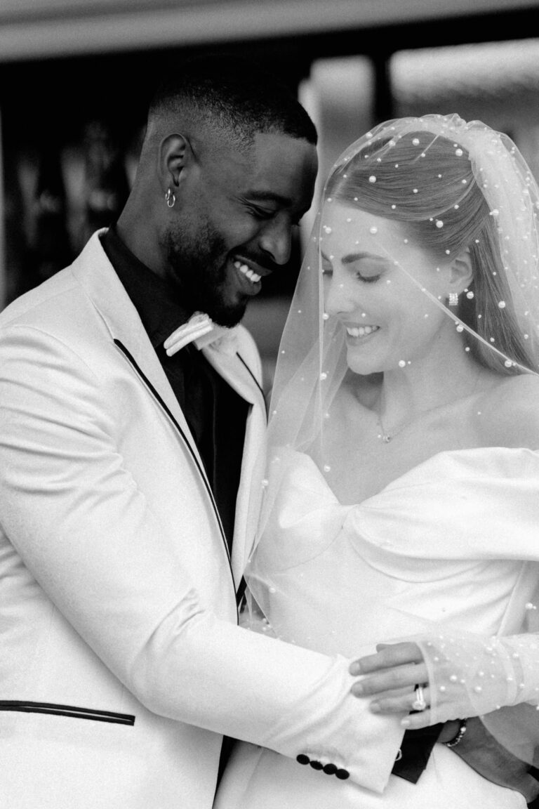 Braut und Bräutigam umarmen sich, lächeln sich herzlich an ihrem Hochzeitstag in der Schweiz an, ein unvergesslicher Moment voller Liebe und perfekter Hochzeitsplanung.