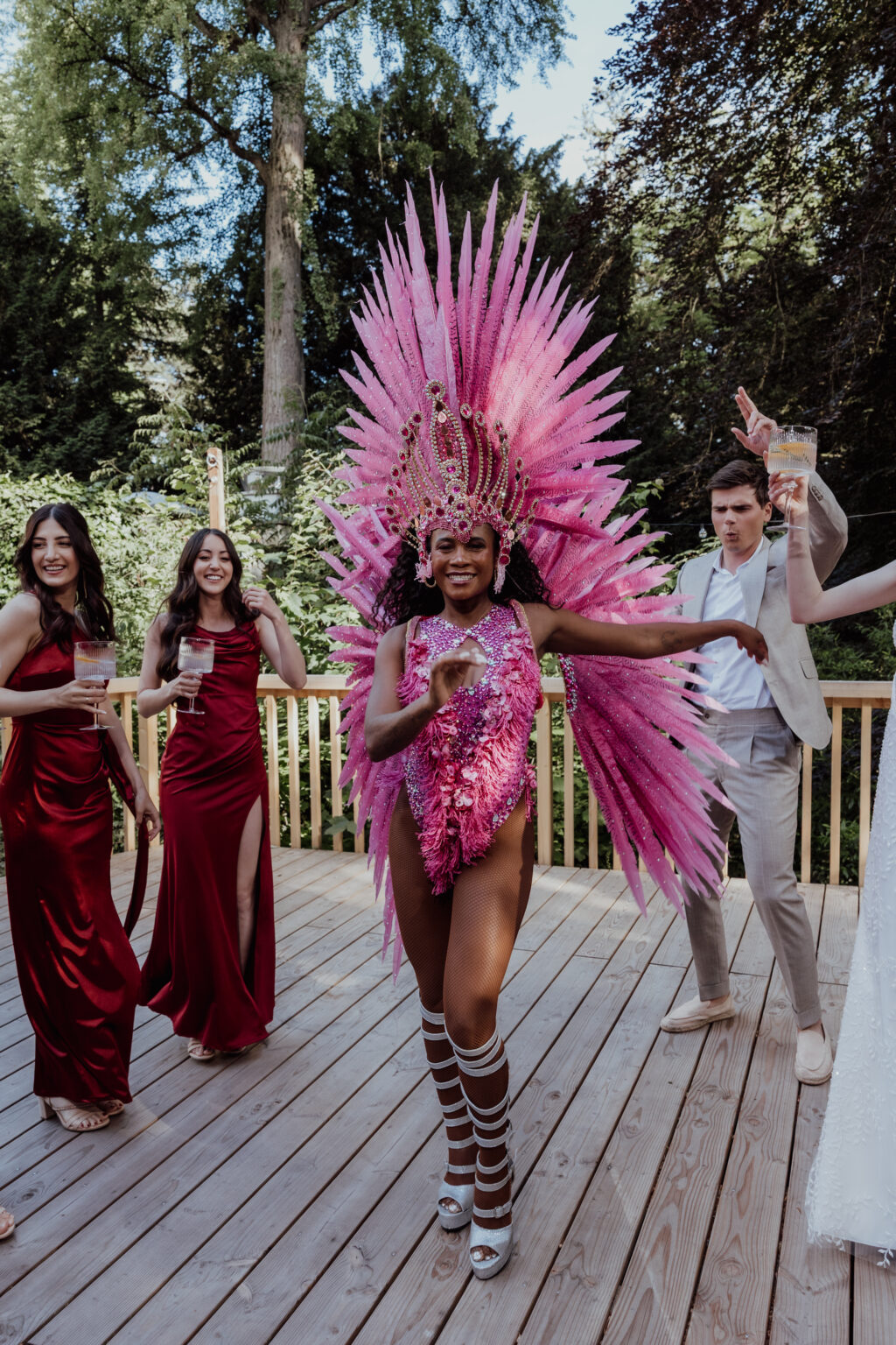 Home 1 Eine Frau in einem leuchtend rosafarbenen Karnevalskostüm tanzt unter freiem Himmel und bezaubert die formell gekleideten Gäste - ein unvergesslicher Moment, inszeniert von einem talentierten Wedding Planner aus der Schweiz und Italien.