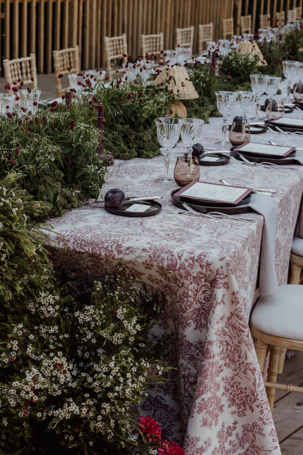 Home 4 Elegantes Tischset für den Außenbereich mit Blumentischdecke, Gläsern, Grünzeug und Blumen - perfekt für eine italienische Hochzeitsplanung oder eine andere formelle Veranstaltung, die von einem professionellen Hochzeitsplaner kuratiert wurde.