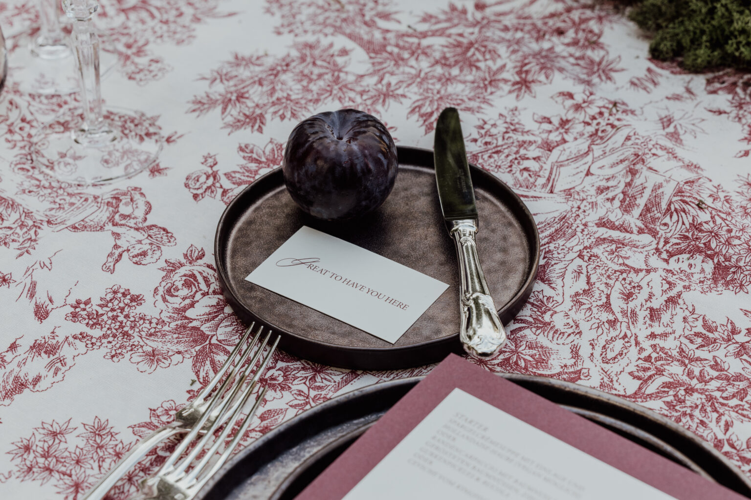 Home 8 Eine violette Pflaume, ein Messer und eine Willkommenskarte auf einem Teller auf einer Blumentischdecke - die perfekte Inspiration für Hochzeitsplaner, die elegante, italienische Details für die Hochzeitsplanung suchen.