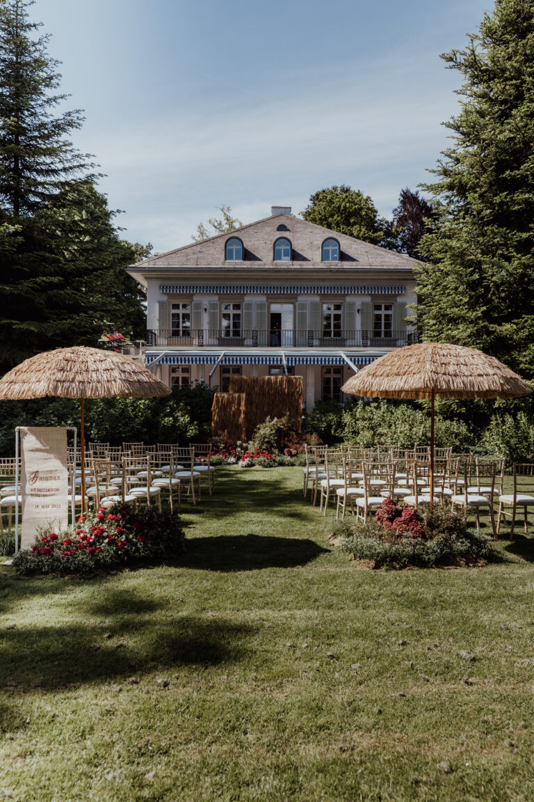 Hochzeitszeremonie im Freien mit Stühlen und Strohschirmen vor einem großen italienischen Haus und Garten - perfekt arrangiert von einem professionellen Hochzeitsplaner.