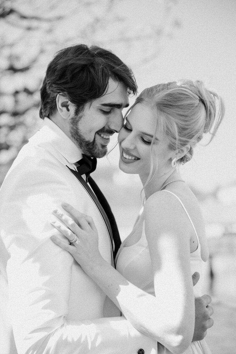 Ein lächelndes Paar umarmt sich im Freien in formeller Kleidung und wirkt glücklich und verliebt während ihrer Hochzeitsplanung in Italien.