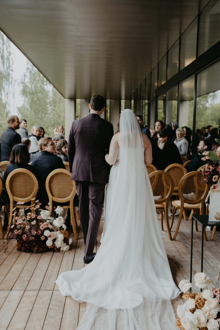 Eine Braut und ein Bräutigam schreiten bei einer Hochzeitszeremonie im Freien in der Schweiz zum Altar, umgeben von sitzenden Gästen - die perfekte Inspiration für Ihre Hochzeitsplanung.