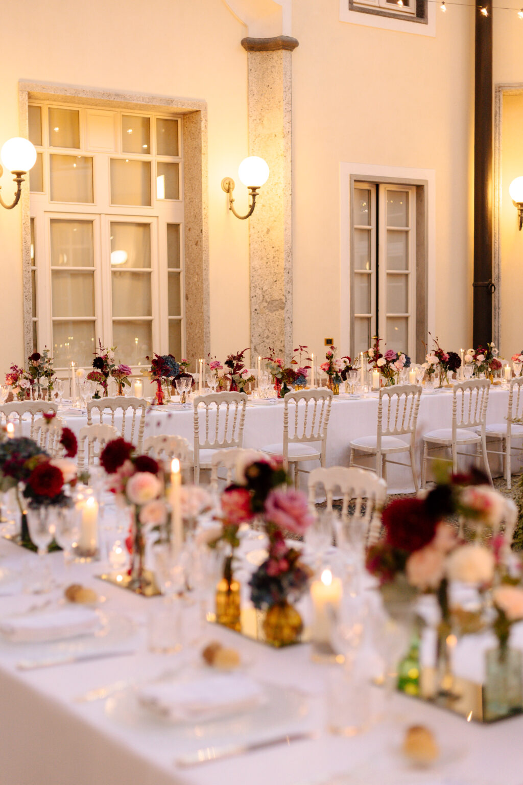 Home 22 Eleganter Hochzeitsempfang im Freien in der Schweiz mit weißen Tischen, Blumenschmuck, Kerzen und klassischen Stühlen in der Abenddämmerung - perfekt koordiniert von Ihrem erfahrenen Wedding Planner.