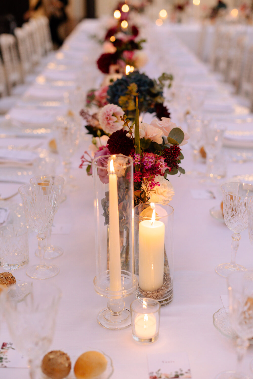 Elegant gedeckter Tisch mit Blumen, Kerzen, Kristallgläsern und Brötchen - die perfekte Inspiration für die Hochzeitsplanung in der Schweiz oder für jede formelle Dinner-Veranstaltung.