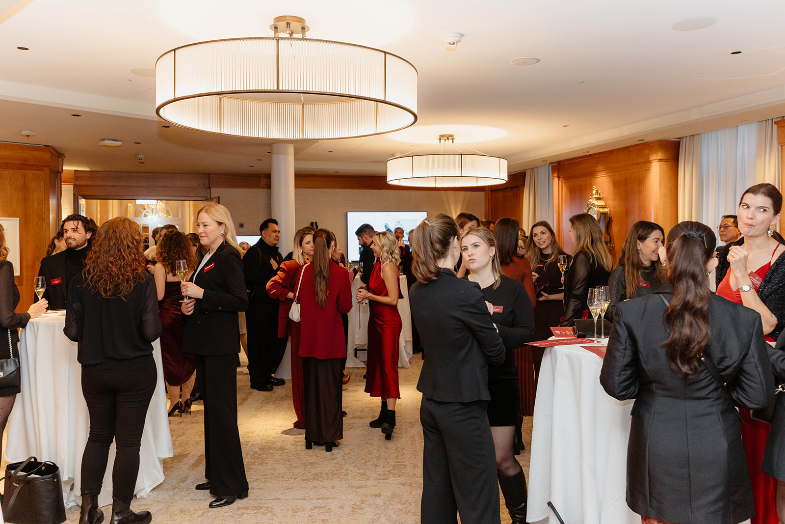 Bei einer Networking-Veranstaltung in einem eleganten, gut beleuchteten Raum mit runden Tischen treffen sich formell gekleidete Menschen. Corporate Events, Networking Events, Firmenevents,
