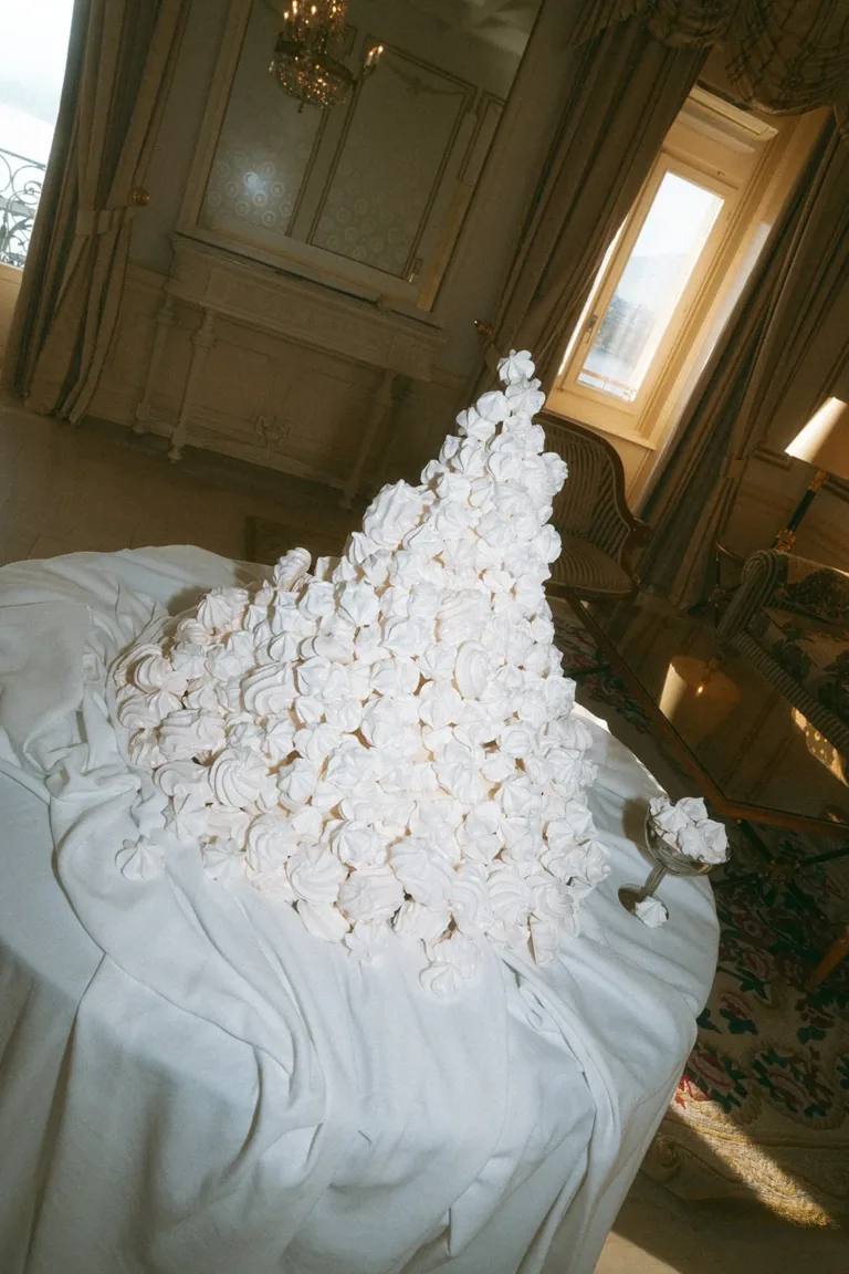 Ein großer Baiserturm auf einem mit Stoff drapierten Tisch für einen Luxus-Hochzeitsplaner in der Schweiz.