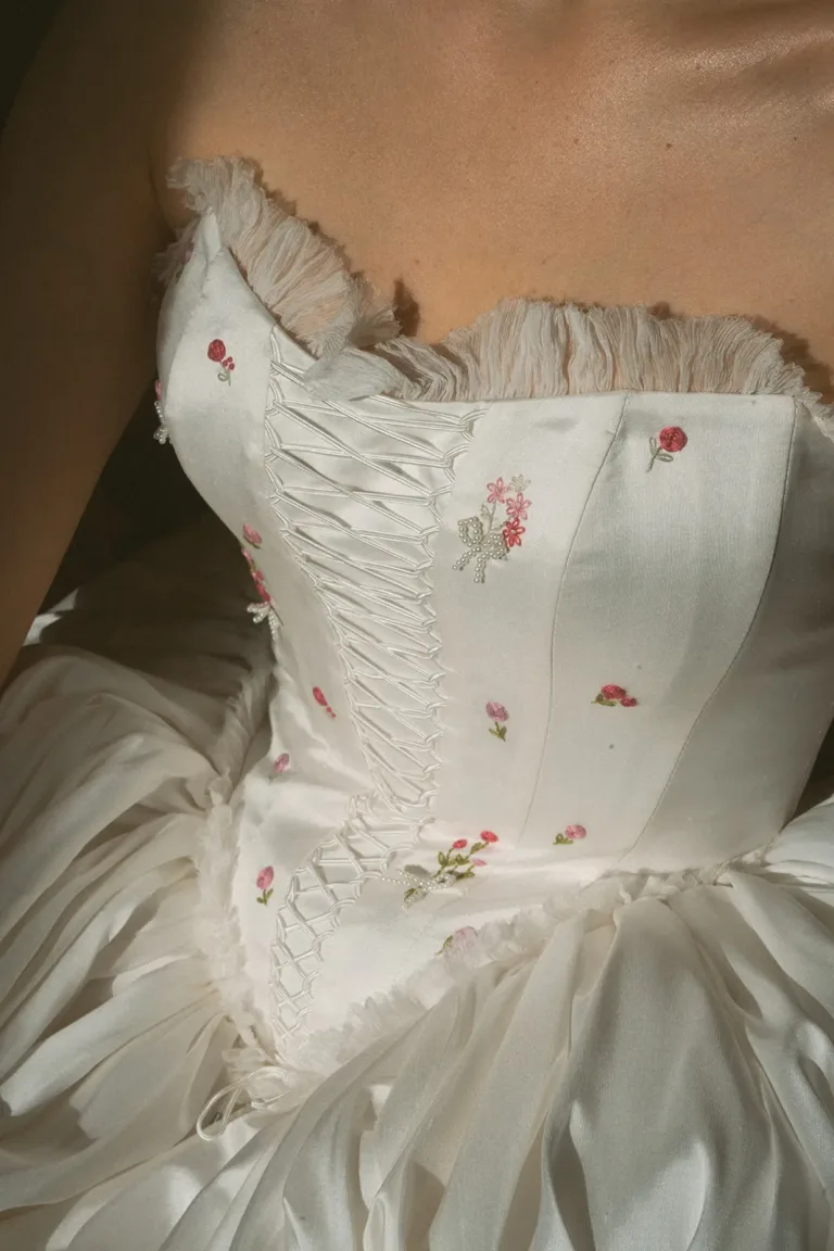Weißes Korsettoberteil mit rosa Blumenstickerei, perfekt für eine Luxus-Hochzeitsplanerin in der Schweiz.