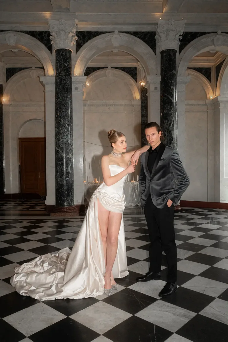 Ein Paar in festlicher Kleidung steht in einer mit Marmor ausgekleideten Halle bei einer Hochzeit in der Schweiz, Luxury Wedding Planner, Zurich, The WES, Switzerland, Schweiz, Lara Flueckiger, Grand Hotel National, Luzern