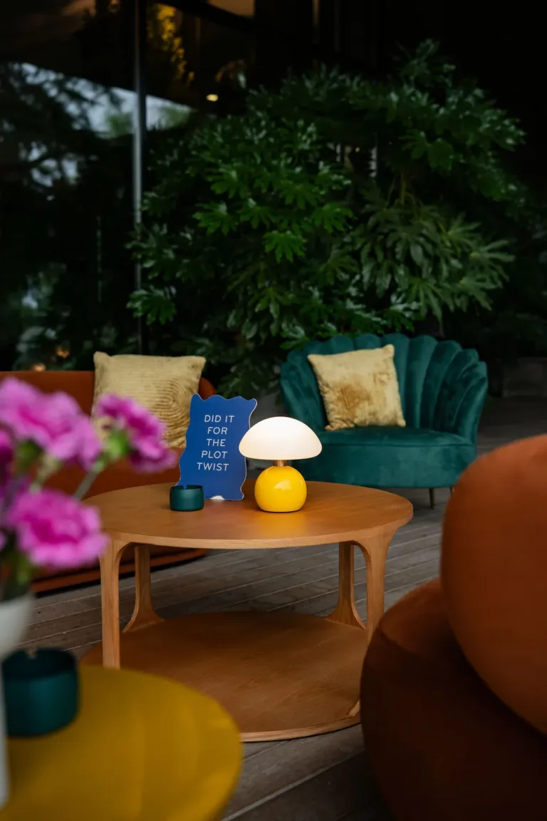 Ein Couchtisch aus Holz mit einer Lampe, einem blauen Schild und Blumen verleiht den Räumlichkeiten von Corporate Events Schweiz eine gemütliche Atmosphäre.