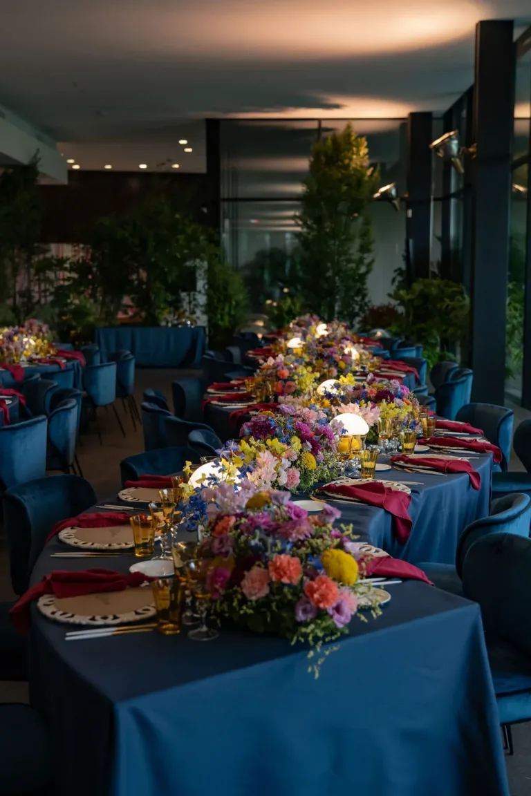 Elegante Tische mit blauen Tischdecken, farbenfrohen Blumenarrangements und sanfter Beleuchtung – perfekt für Firmenveranstaltungen in der Schweiz.